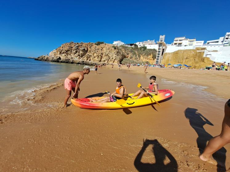 Duas crianças dentro de um kayak a entrar no mar na praia do peneco